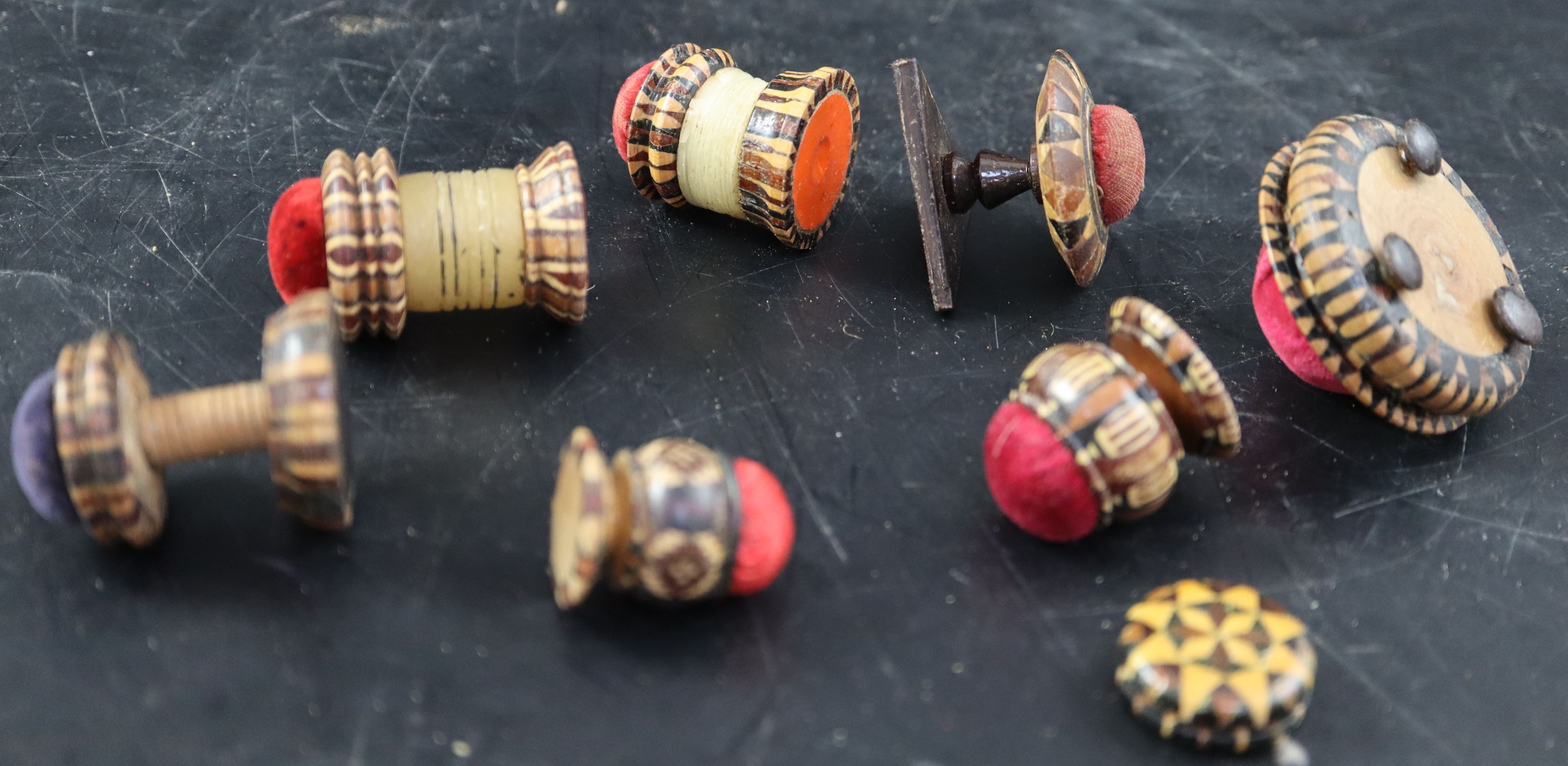 Seven assorted Victorian Tunbridgeware pin cushions and a small spool